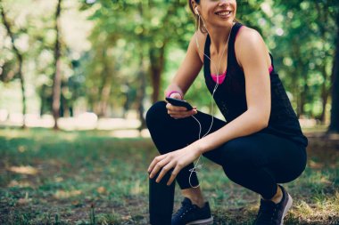 Beyaz tenli genç bayan koşucu koşmaktan dinleniyor ve dinleniyor..