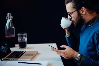 Ofisinde oturan ve akıllı telefon kullanan hippilerin yan görüntüsü..