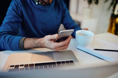 Ofisindeki kahve molasında akıllı telefon kullanan serbest çalışan biri..