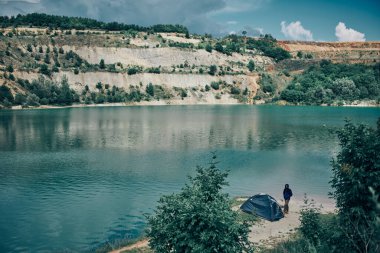 Kamp gezisinde çadırın yanında duran ve güzel doğaya hayran olan bir adam..