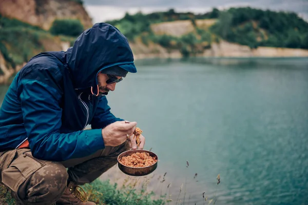 Young Man Crouching Lake Having Spaghetti Lunch Camping Trip — Stock Photo, Image