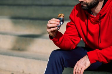 Koşucunun merdivenlerde oturduğu ve koştuktan sonra enerji çubuğu yediği yakın plan..