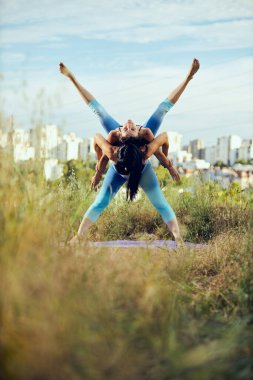 İki güçlü kadın dışarıda akroyoga yapıyor..