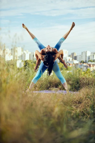 İki güçlü kadın dışarıda akroyoga yapıyor..