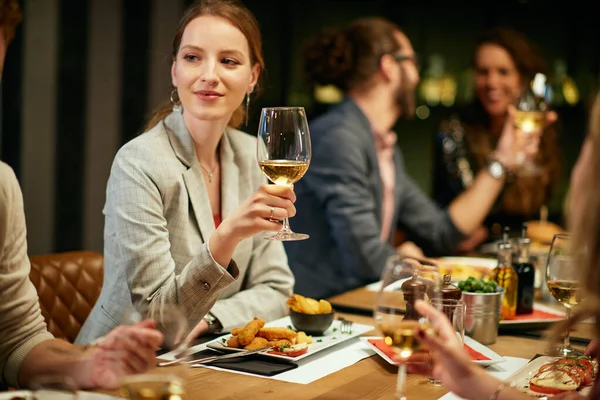 Hermosa Mujer Sentada Restaurante Con Amigos Sosteniendo Una Copa Vino —  Fotos de Stock
