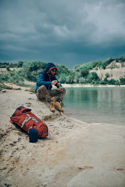 Ung Attraktiv Man Sitter Sjön Stranden Och Äter Sin Lunch — Stockfoto