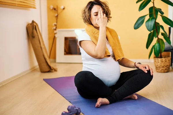 中年フィット妊娠中のヨギ女性は自宅で床に座って呼吸法を行います — ストック写真