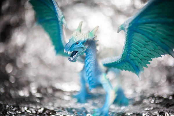 Ice blue dragon toy photo on blur bokeh background, winter cool colors tone