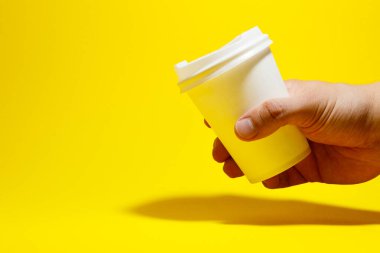 Sarı arka planda izole edilmiş beyaz kağıt kahve fincanı.