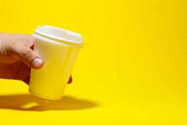 Sarı arka planda izole edilmiş beyaz kağıt kahve fincanı.