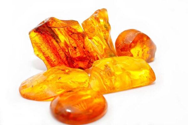 A lot of pieces of transparent yellow and red amber on a white background. Semi-precious mineral. Sun stone. Colored patterns. Amber texture. Frozen ancient resin. Material for jewelers. Amber pieces with inclusions. Geology