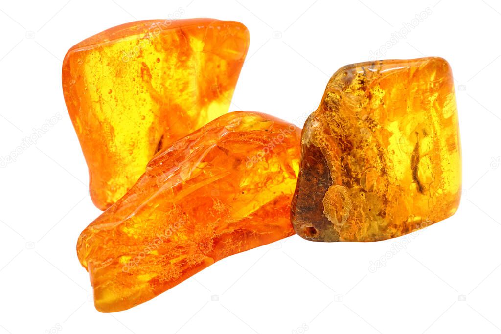 Three pieces of transparent yellow amber on a white background. Semi-precious mineral. Sun stone. Colored patterns. Amber texture. Frozen ancient resin. Material for jewelers. Amber pieces with inclusions. Geology
