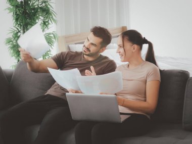 Çift evde dizüstü bilgisayar ve kağıt dökümanları üzerinde çalışıyor, çevrimiçi bilgi ve alışverişi arıyor, gençler iş görüşmesi için sosyal medyayı kullanıyor, yeni normal iş formu ev kavramı