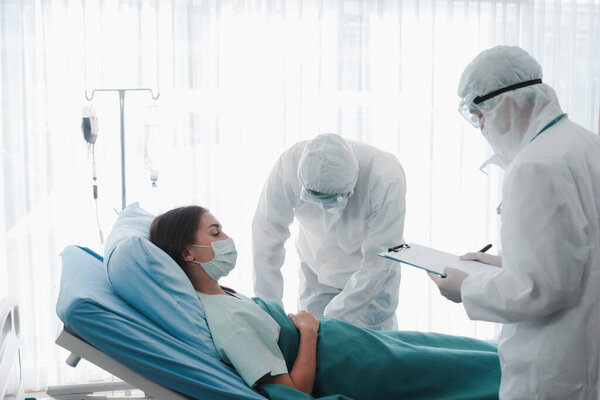 Зал лечения заболеваний для инфицированных пациентов, инфицированных женщин, лежащих в постели с врачом в защитной одежде в карантине в больнице, заботиться о больных
