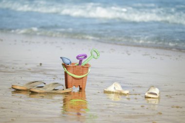 Çocukların plaj oyuncakları ve turuncu kova. Yaz mevsiminde mavi denizli tropikal kum plajı.