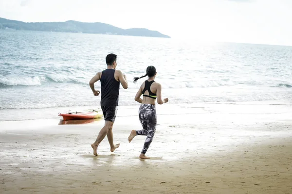 Young runner jogging outdoor on summer tropical island beach with blue sea, doing exercise outdoor, sport guy jogger athlete doing and training workout outdoor