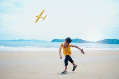 Tatlı çocuk kumlu yaz kumsalında mavi denizle eğleniyor. Mutlu çocukluk çocuğu tropik sahilde model uçak oynuyor.