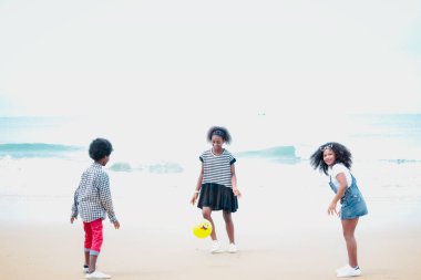 Şirin çocuklar kumlu yaz sahillerinde mavi denizle birlikte eğleniyorlar. Mutlu çocukluk arkadaşları tropikal plajda top oynuyorlar. 