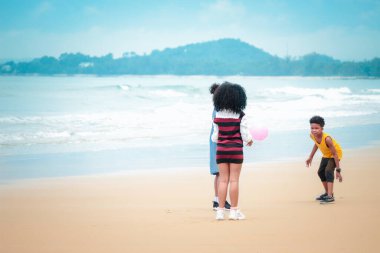 Şirin çocuklar kumlu yaz sahillerinde mavi denizle birlikte eğleniyorlar. Mutlu çocukluk arkadaşları tropikal plajda top oynuyorlar. 