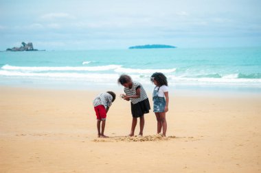 Tatlı çocuklar kumlu yaz sahillerinde mavi denizle birlikte eğleniyorlar. Mutlu çocukluk arkadaşları tropikal plajda oynuyorlar.