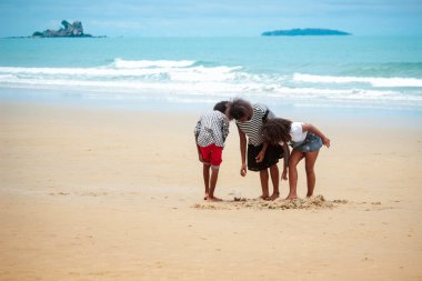 Tatlı çocuklar kumlu yaz sahillerinde mavi denizle birlikte eğleniyorlar. Mutlu çocukluk arkadaşları tropikal plajda oynuyorlar.