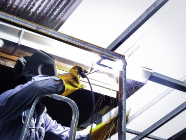 Fabrikada güvenlik maskesi, kask ve metal kaynaklama gözlüğü takan endüstriyel işçiler. Fabrikada çalışan endüstriyel makine mühendisi çelik kaynak yapısında.