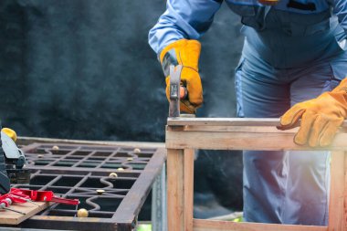 Güvenlik ekipmanı takan işçiler, tamir ve bakım için çekiç tutan marangozlar, tahta mobilyaları tamir etmek için çivi çakan çekiçli adamlar.