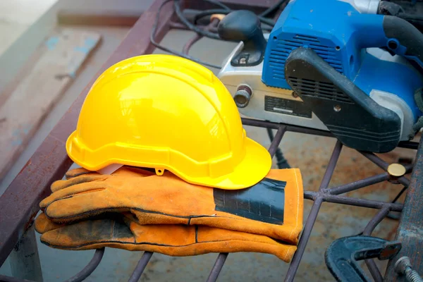 İnşaat alanında sarı güvenlik kaskı ve güvenlik eldivenleri.  