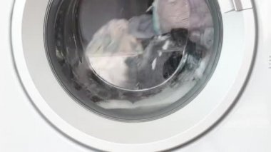 Çamaşır makinesi içinde dönen giysilerle çalışıyor, çamaşır makinesiyle bez temizleme işlemi, çamaşır konsepti