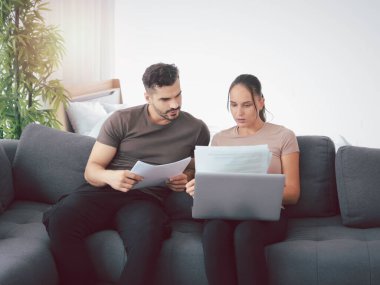 Çift evde dizüstü bilgisayar ve kağıt dökümanları üzerinde çalışıyor, çevrimiçi bilgi ve alışverişi arıyor, gençler iş görüşmesi için sosyal medyayı kullanıyor, yeni normal iş formu ev kavramı