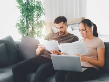 Çift evde dizüstü bilgisayar ve kağıt dökümanları üzerinde çalışıyor, çevrimiçi bilgi ve alışverişi arıyor, gençler iş görüşmesi için sosyal medyayı kullanıyor, yeni normal iş formu ev kavramı