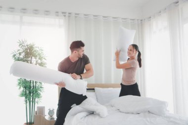 Yatakta yastık başında kavga eden çift, yatak odasında yastık savaşıyla eğlenen sevgili, yatakta tartışan evli çift.