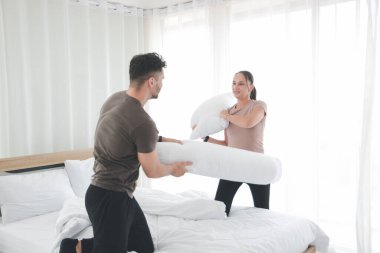 Yatakta yastık başında kavga eden çift, yatak odasında yastık savaşıyla eğlenen sevgili, yatakta tartışan evli çift.