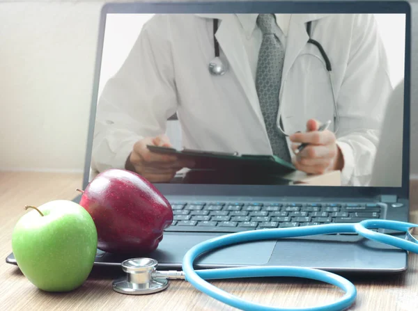 Doctor online concept, red and green apple with stethoscope and doctor on computer laptop for consultation with patient, medical communication and medical consultant in nutrition on virtual interface