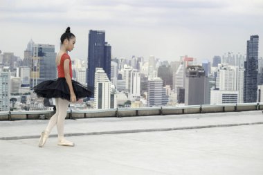 Asyalı balerin kız çatıda bale yapıyor gökdelen manzaralı, bale yapan sevimli çocuk.