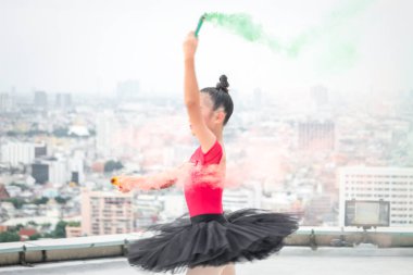 Asyalı balerin kız çatıda renkli sis bombasıyla dans ediyor gökdelen manzaralı, balede dans eden sevimli çocuk. 