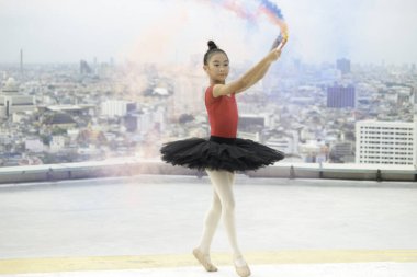 Asyalı balerin kız çatıda renkli sis bombasıyla dans ediyor gökdelen manzaralı, balede dans eden sevimli çocuk. 