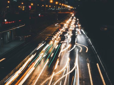 Geceleyin sokakta uzun ışık izleri, yol üzerindeki arabaların bulanık izleriyle hareket hızı trafik ışığı. 