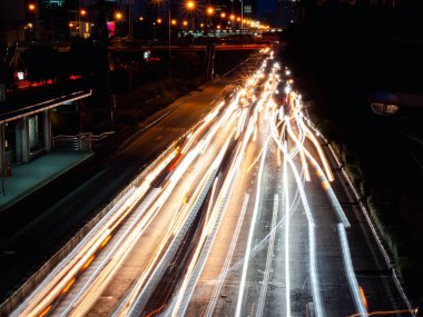 Geceleyin sokakta uzun ışık izleri, yol üzerindeki arabaların bulanık izleriyle hareket hızı trafik ışığı. 