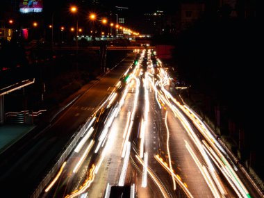 Geceleyin sokakta uzun ışık izleri, yol üzerindeki arabaların bulanık izleriyle hareket hızı trafik ışığı. 