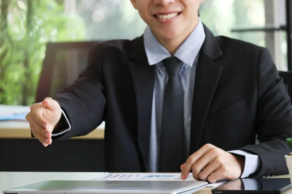 Businessman in suit giving hand for handshake with copyspace, man with open hand ready to seal a deal at workplace