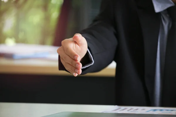 Businessman in suit giving hand for handshake with copyspace, man with open hand ready to seal a deal at workplace