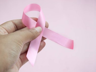 Göğüs kanseri tutan eller pembe arka planda pembe kurdele, Ekim sembolü, sağlık ve tıp konsepti