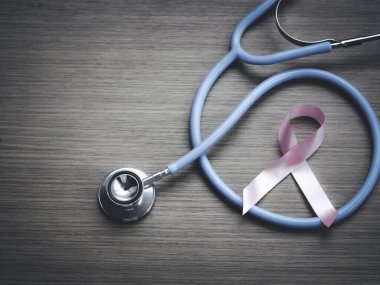 Göğüs kanseri farkındalığı. Ahşap arka planda doktor steteskobu olan pembe kurdele. Ekim sembolü, sağlık ve tıp konsepti.