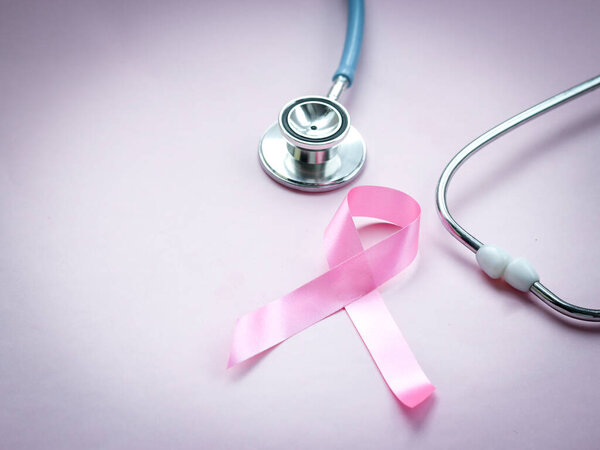 Breast cancer awareness pink ribbon with doctor stethoscope on pink background, october symbol, healthcare and medicine concept 