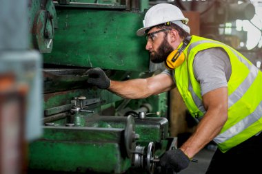 Kasklı ve güvenli gözlükler takan endüstri mühendisi fabrika fabrikasında makinelerle çalışıyor, endüstri konseptinde makine ile çalışıyor.