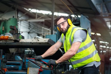 Kasklı ve güvenli gözlükler takan endüstri mühendisi fabrika fabrikasında makinelerle çalışıyor, endüstri konseptinde makine ile çalışıyor.
