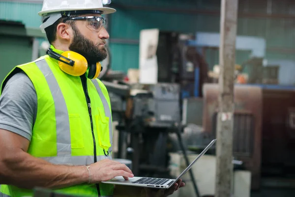 工业工程师 头戴安全帽 戴着安全眼镜 手持手提电脑 在工厂工厂操作机器 与机器一起工作的工业概念 — 图库照片