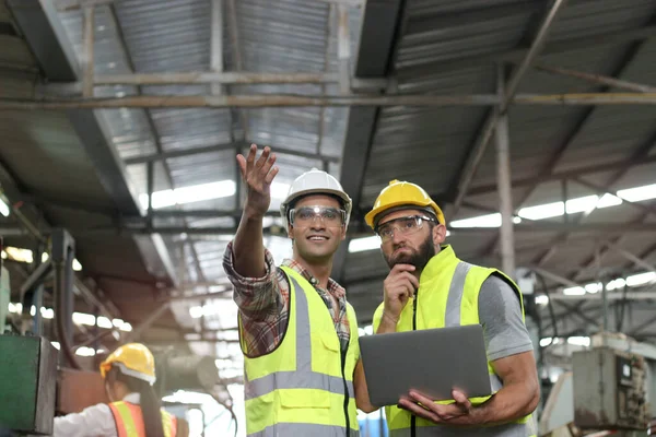 工业工程师头戴安全帽 戴着安全眼镜 手持手提电脑 在工厂工厂操作机器 工人团队在工业理念上携手合作 — 图库照片