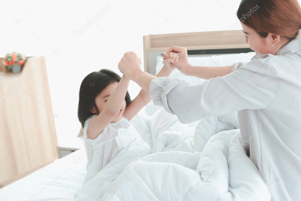Happy family having fun in the bedroom. Mother, and daughter spending time together, little girl playing with her mom on bed, parents and kid having good memory together at home